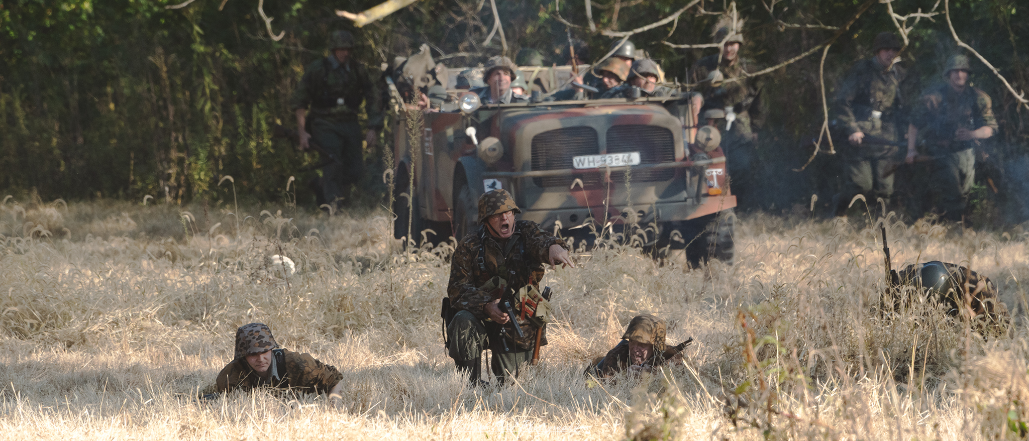 "Image depicting a German assault during World War II, showcasing soldiers advancing with determination. The scene captures the intensity of battle, with soldiers in Wehrmacht uniforms, armed with rifles and grenades, moving through a war-torn landscape. Smoke rises in the background, and debris litter the ground, illustrating the chaos of warfare. The atmosphere is tense, highlighting the bravery and resolve of the soldiers in the midst of combat."